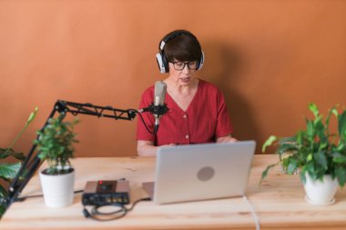 Middle-aged woman radio host making podcast recording for online show - broadcast and dj concept