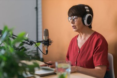 Middle-aged woman radio host making podcast recording for online show - broadcast and dj concept