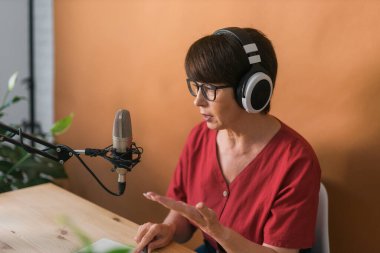 Middle-aged woman radio host making podcast recording for online show - broadcast and dj concept