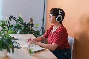 Middle-aged female radio presenter talking into the microphone and reading news - radio broadcast online concept