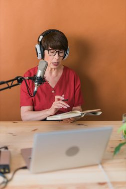 Middle-aged female radio presenter talking into the microphone and reading news - radio broadcast online concept
