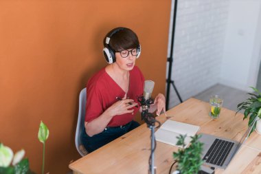 Middle-aged female radio presenter talking into the microphone and reading news - radio broadcast online concept