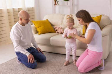 Cochlear implant on the child girl head and playing with mother and father. Hearing aid and deafness and innovative health technology concept