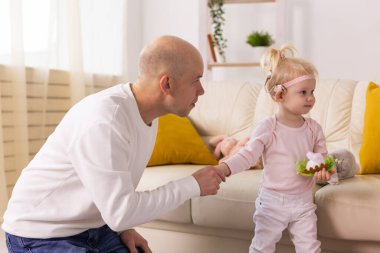 Baby child with hearing aids and cochlear implants plays with father on floor. Deaf and rehabilitation concept