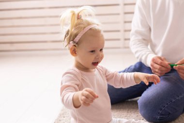 Cochlear implant for baby. Deaf child with hearing aid plays in living room.
