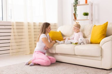 Child girl with cochlear implant with her mother at home. Hear impairment and deaf community concept
