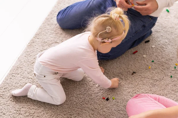 Cochlear implant for baby. Deaf child with hearing aid plays in living room top view