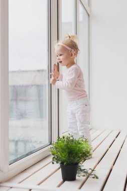 Funny baby with cochlear implant sitting at home and eating. Hear aid and medicine innovating technology concept