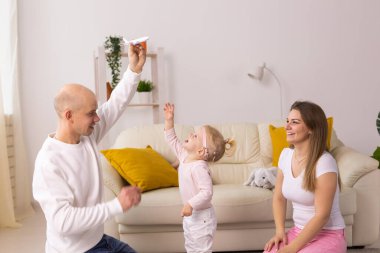 İşitme cihazı ve koklear implantı olan bebek anne babasıyla yerde oynuyor. Sağır ve rehabilitasyon kavramı