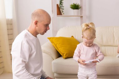 Baby with cochlear implants playing with her father at home. Deafness and medical technology concept