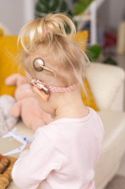 Koklear implantı olan bebek evde eğleniyor. Sağırlık ve tıbbi teknoloji kavramı.