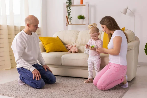 İşitme cihazı ve koklear implantı olan bebek anne babasıyla yerde oynuyor. Sağır ve rehabilitasyon kavramı