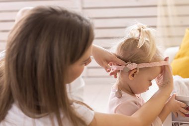 Mother helps her baby put on part of cochlear implant - Deaf child with hearing aid at home