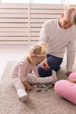 Happy child girl with cochlear implant having fun with her father - hearing aid for deaf and innovative health technology concept