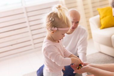 Baby girl with cochlear implants playing with her father at home. Deafness and medical technology concept