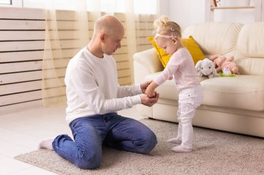 Happy child girl with cochlear implant having fun with her father - hearing aid for deaf and innovative health technology concept