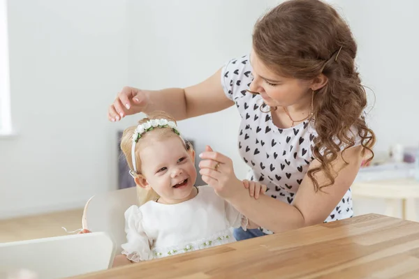 Mother helps her deaf baby daughter putting hearing aid in little girls ear indoors - cochlear implant and innovative medical technologies in the treatment of deafness