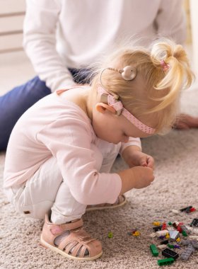 Cochlear implant for baby. Deaf child with hearing aid plays in living room.