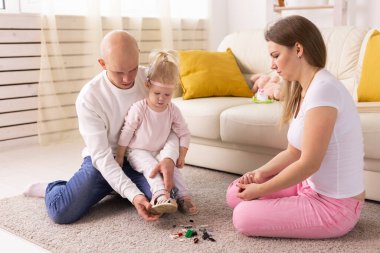 Cochlear implant on the child girl head and playing with mother and father. Hearing aid and deafness and innovative health technology concept