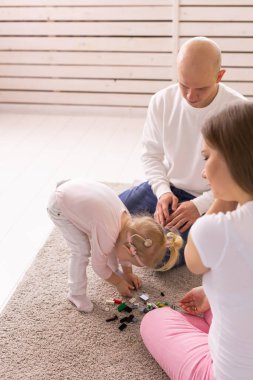 Cochlear implant on the child girl head and playing with mother and father. Hearing aid and deafness and innovative health technology concept