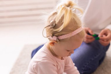 Happy child girl with cochlear implant having fun with her father - hearing aid for deaf and innovative health technology and diversity concept