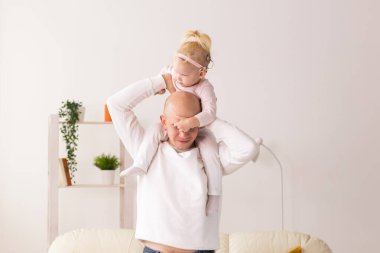 Happy child girl with cochlear implant having fun with her father - hearing aid for deaf and innovative health technology and diversity concept