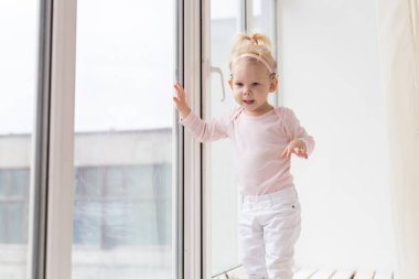 Funny baby with cochlear implant sitting at home and eating. Hear aid and medicine innovating technology concept - copy space and place for advertising