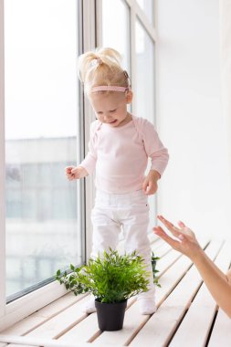 Funny baby with cochlear implant sitting at home and eating. Hear aid and medicine innovating technology and diversity concept