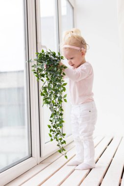 Funny baby with cochlear implant sitting at home and eating. Hear aid and medicine innovating technology and diversity concept