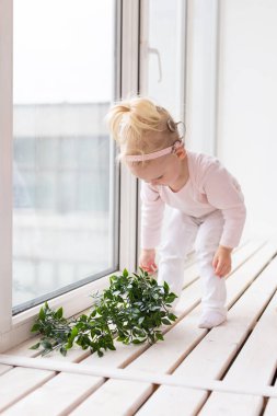 Funny baby with cochlear implant sitting at home and eating. Hear aid and medicine innovating technology and diversity concept