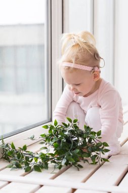 Funny baby with cochlear implant sitting at home and eating. Hear aid and medicine innovating technology and diversity concept