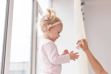 Baby with cochlear implants at home. Deafness and medical technology and diversity concept.