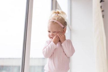 Funny baby with cochlear implant sitting at home and eating. Hear aid and medicine innovating technology and diversity concept - copy space and place for advertising