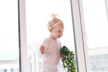 Funny baby with cochlear implant sitting at home and eating. Hear aid and medicine innovating technology concept