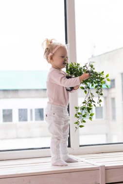 Funny baby with cochlear implant sitting at home and eating. Hear aid and medicine innovating technology concept