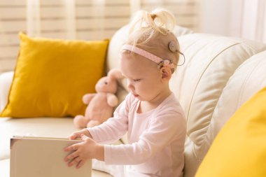 Cochlear implant for baby. Deaf child with hearing aid at home - diversity concept