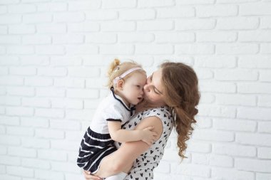 Baby with cochlear implant hearing aid having fun with her mother - deafness and diversity concept. Copy space and place for advertising