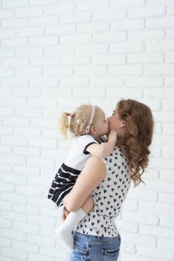 Baby with cochlear implant hearing aid having fun with her mother - deafness and diversity concept. Copy space and place for advertising