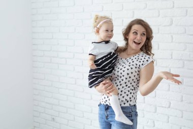 Baby with cochlear implant hearing aid having fun with her mother - deafness and diversity concept. Copy space and place for advertising