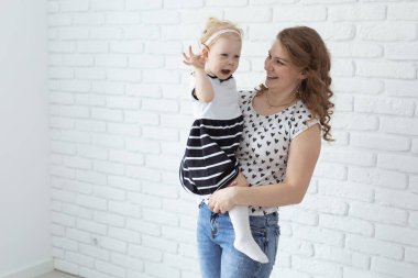Mother helps her deaf baby daughter putting hearing aid in little girls ear indoors - cochlear implant and innovative medical technologies