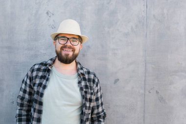 guy tourist looking happy wearing straw hat for travelling, standing against concrete wall background with copy space