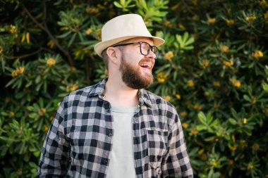 Close up portrait handsome young man over green bush outside copy space and place for advertising
