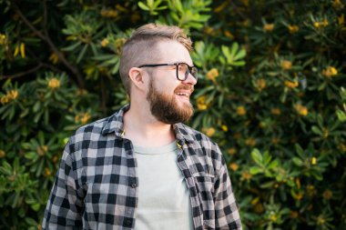 Close up portrait handsome young man over green bush outside copy space and place for advertising