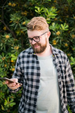 Laughing attractive man wearing hat over green tree background - emotion and vacation travel holidays