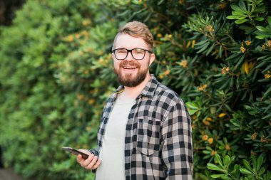 Laughing attractive man wearing hat over green tree background - emotion and vacation travel holidays