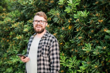 Close up portrait handsome young man over green bush outside copy space and place for advertising