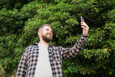 Man taking selfie portrait over palm tree background - Happy millennial guy enjoying summer holidays in city - Youth and technologies.