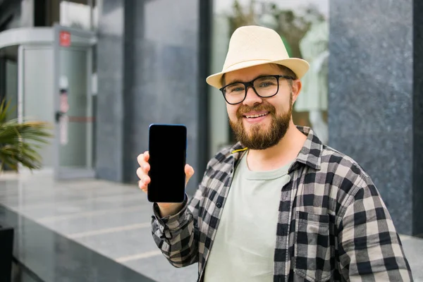 Hot offering. Happy guy holds cellphone with black copy space and smiling. Human emotions facial place for advertising and text