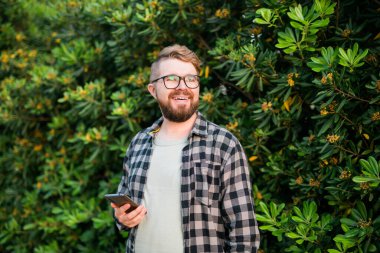 Portrait of attractive cheerful guy using smartphone for scrolling on social media over bright vivid shine vibrant yellow color