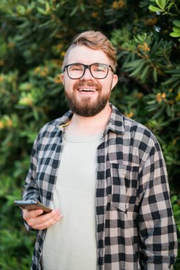 Portrait of attractive cheerful guy using smartphone for scrolling on social media over bright vivid shine vibrant yellow color